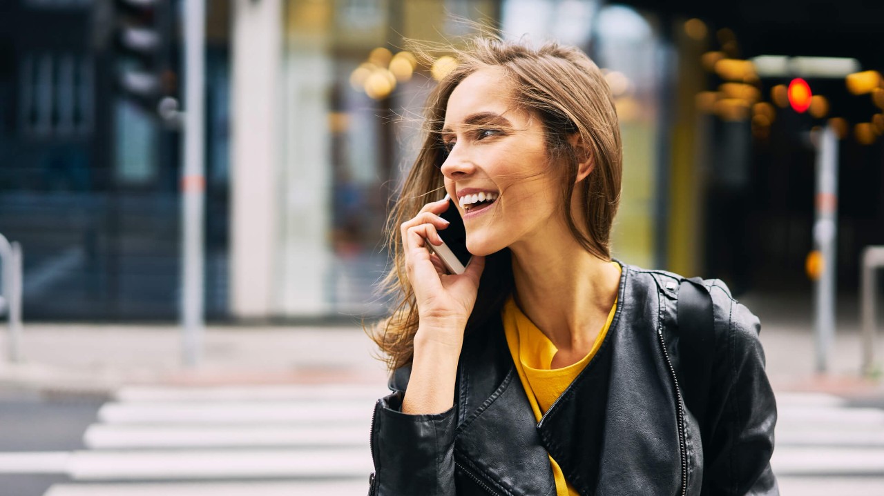 Woman crossing the street talking on the phone using the DISH Wireless 5G network